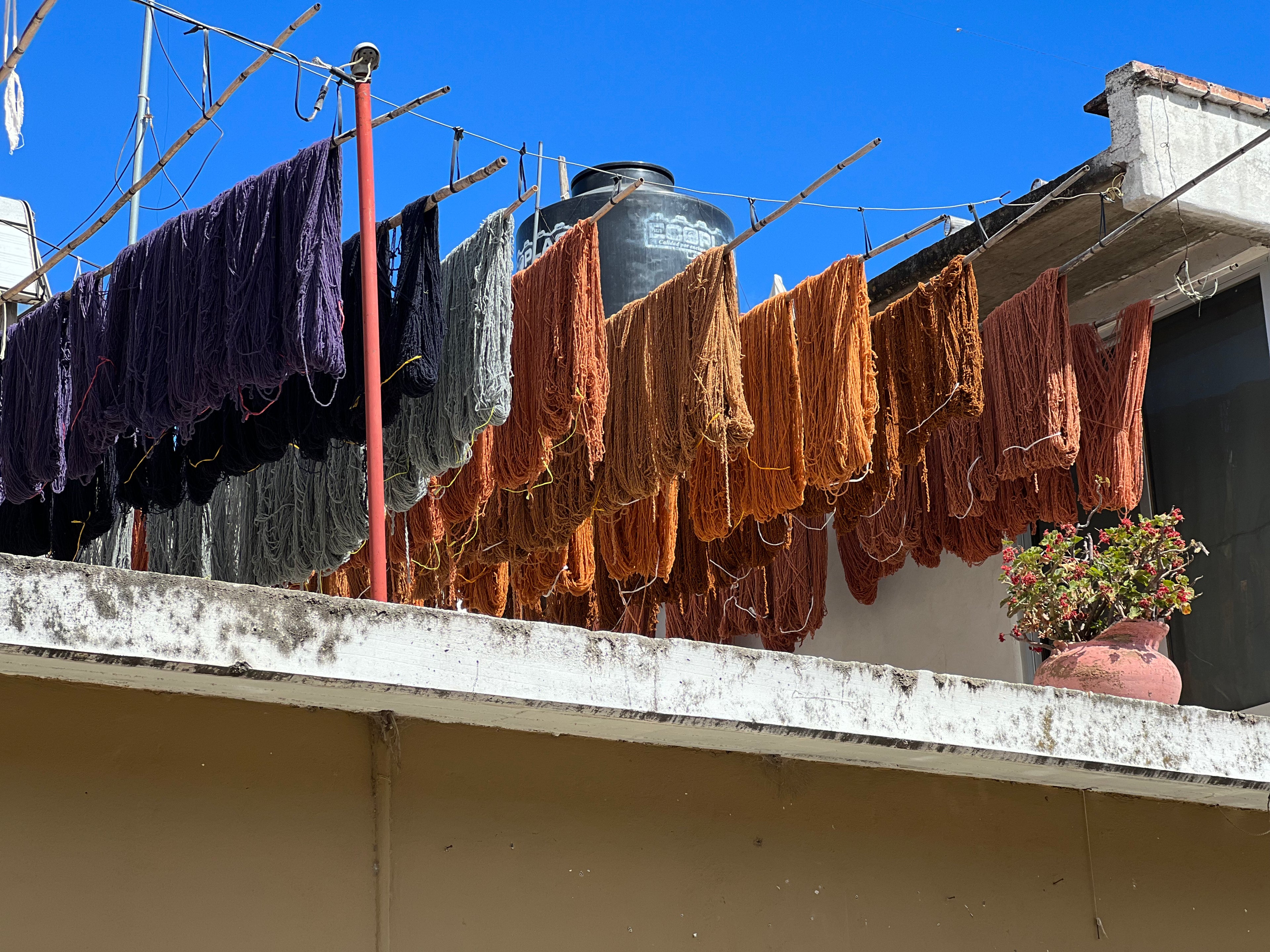 Drying clothes on a line against a blue sky with a water tank in the background.