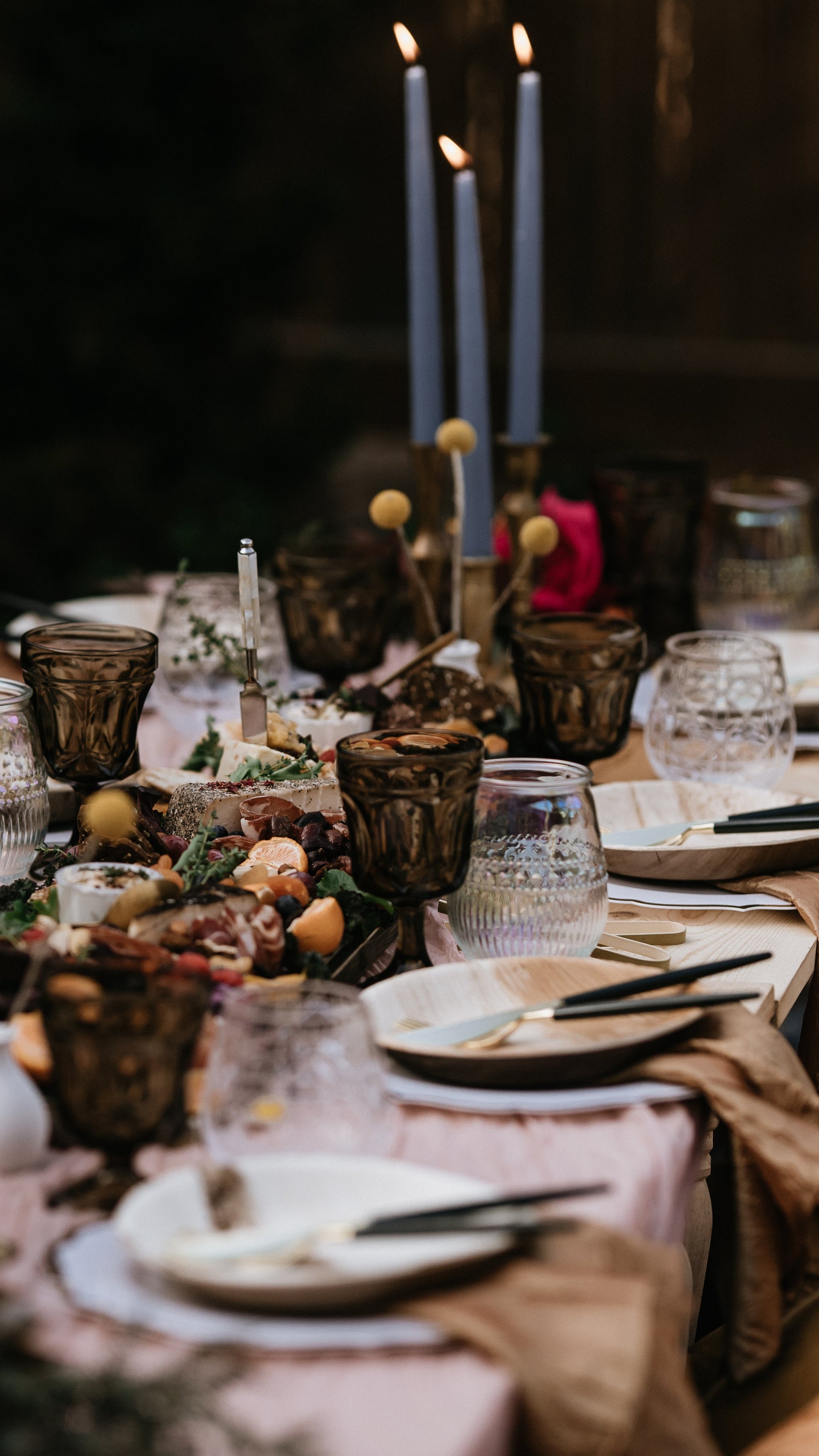 Decorative table setting with candles and flowers in a dimly lit room. Asheville Luxury Picnics picnic pop up avl.