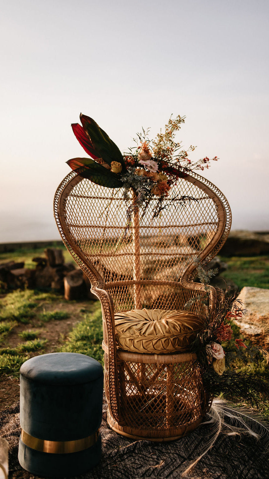 Wicker chair with floral arrangement and feathers in a natural setting  asheville luxury picnics. pop-up picnic. picnic pop-up avl
