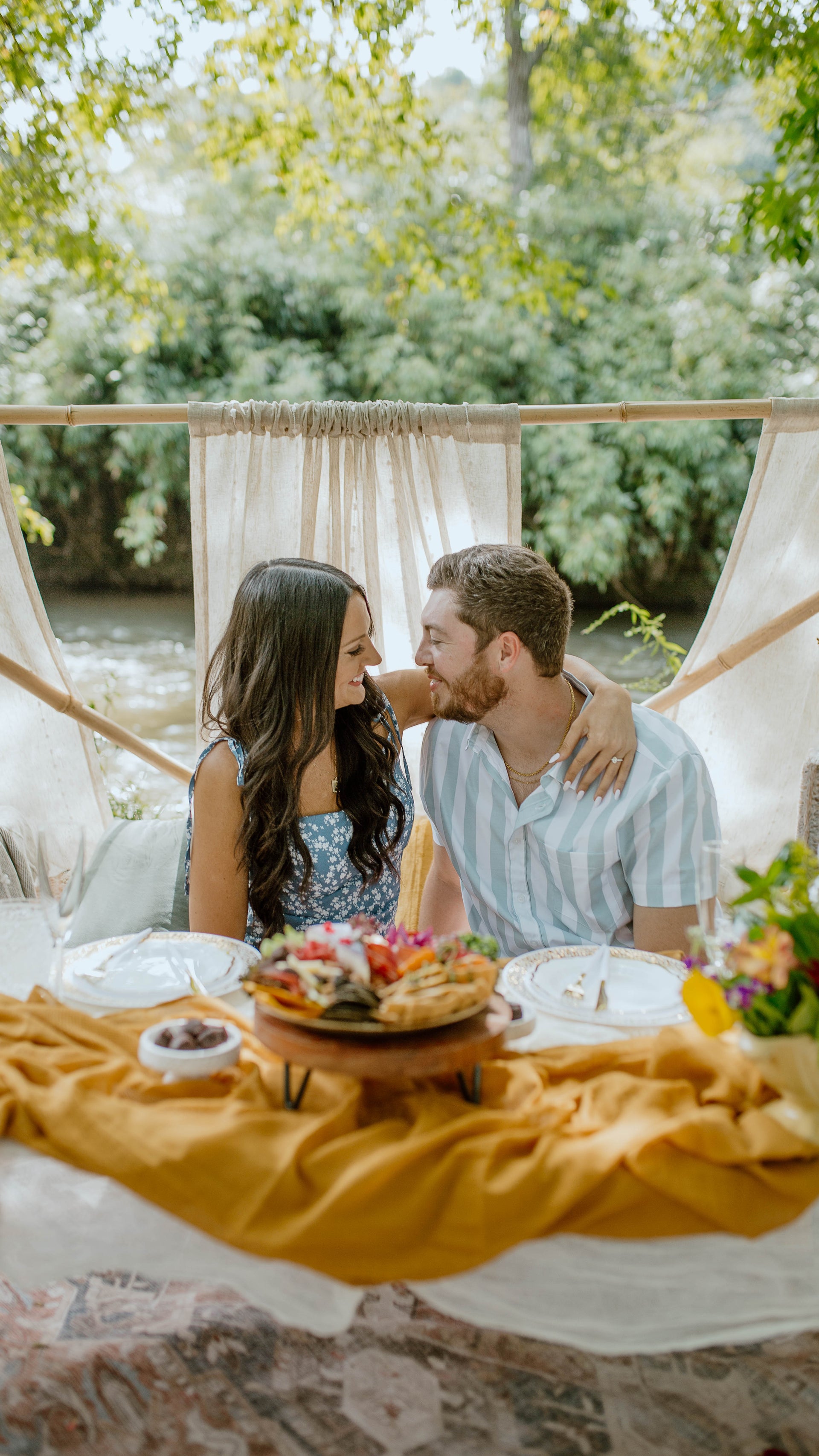 Couple sharing a romantic moment at a picnic table with a scenic background.  asheville luxury picnics. pop-up picnic. picnic pop-up avl