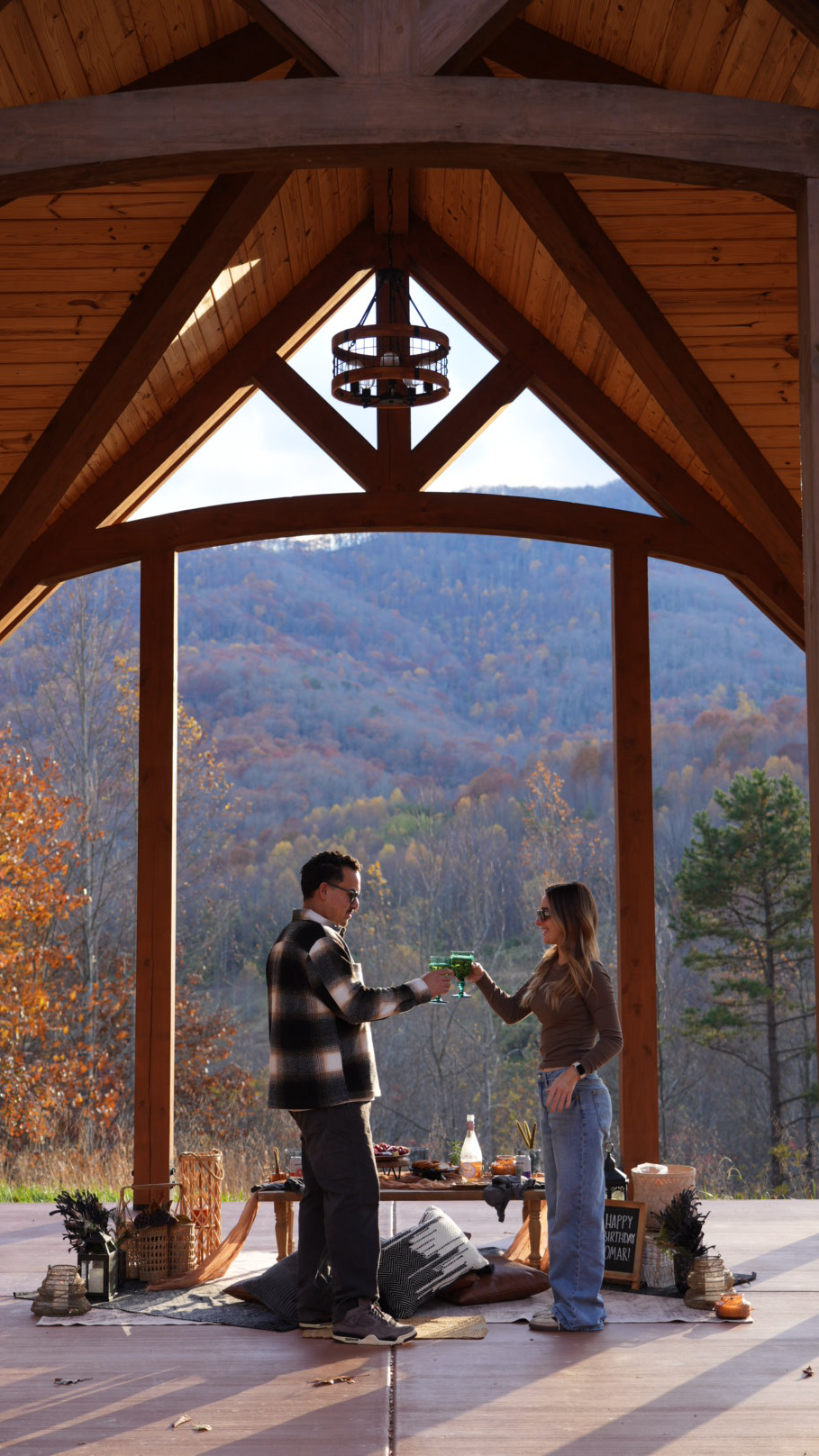Two people standing on a wooden deck with a scenic mountain view.  asheville luxury picnics. pop-up picnic. picnic pop-up avl