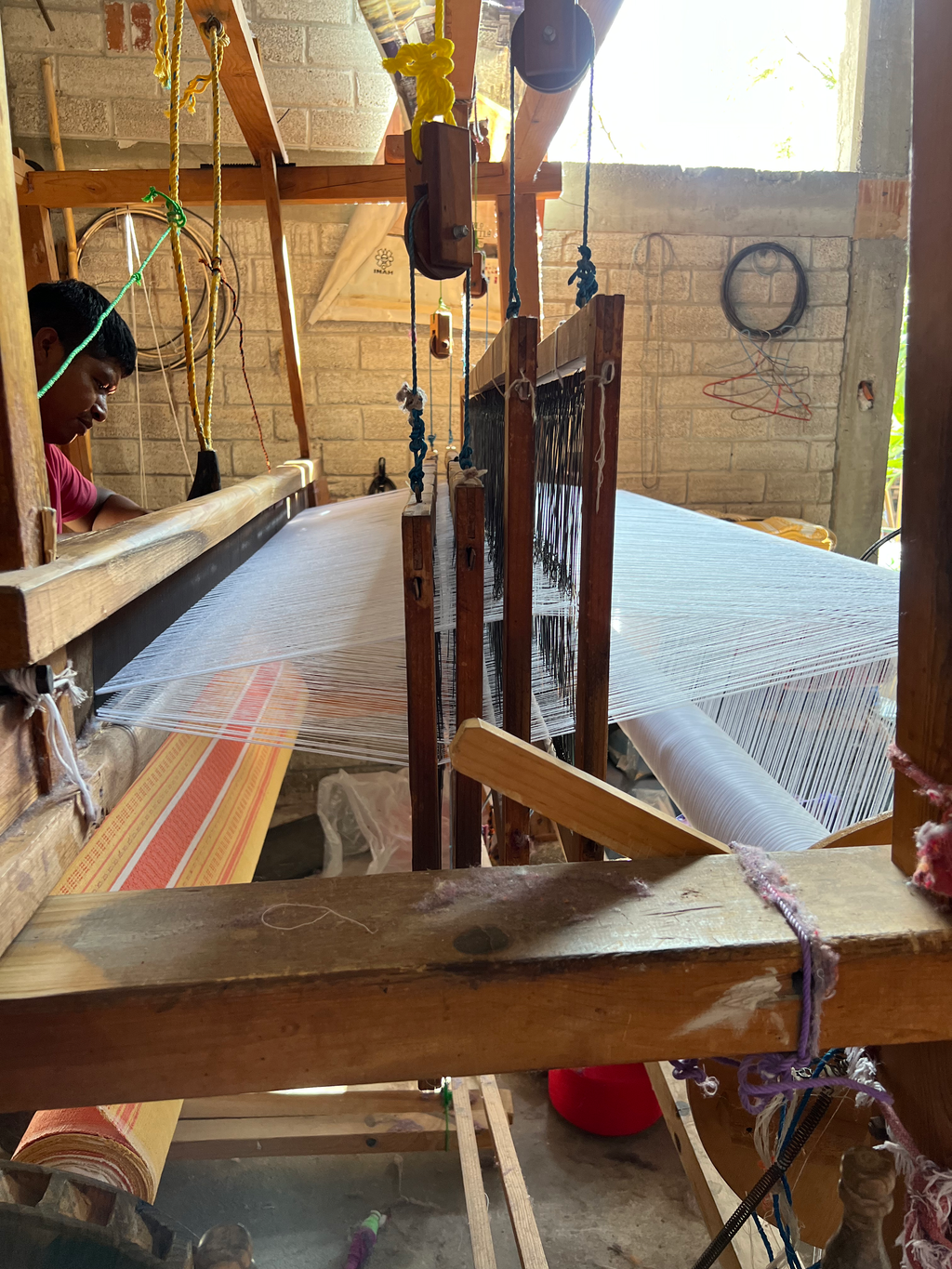 Person working with a wooden loom in a workshop setting