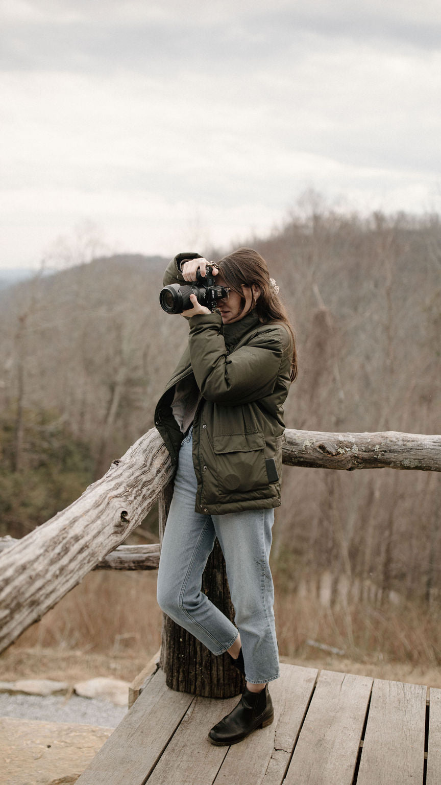 Person taking a photograph on a wooden platform with a forest   asheville luxury picnics. pop-up picnic. picnic pop-up avlbackground
