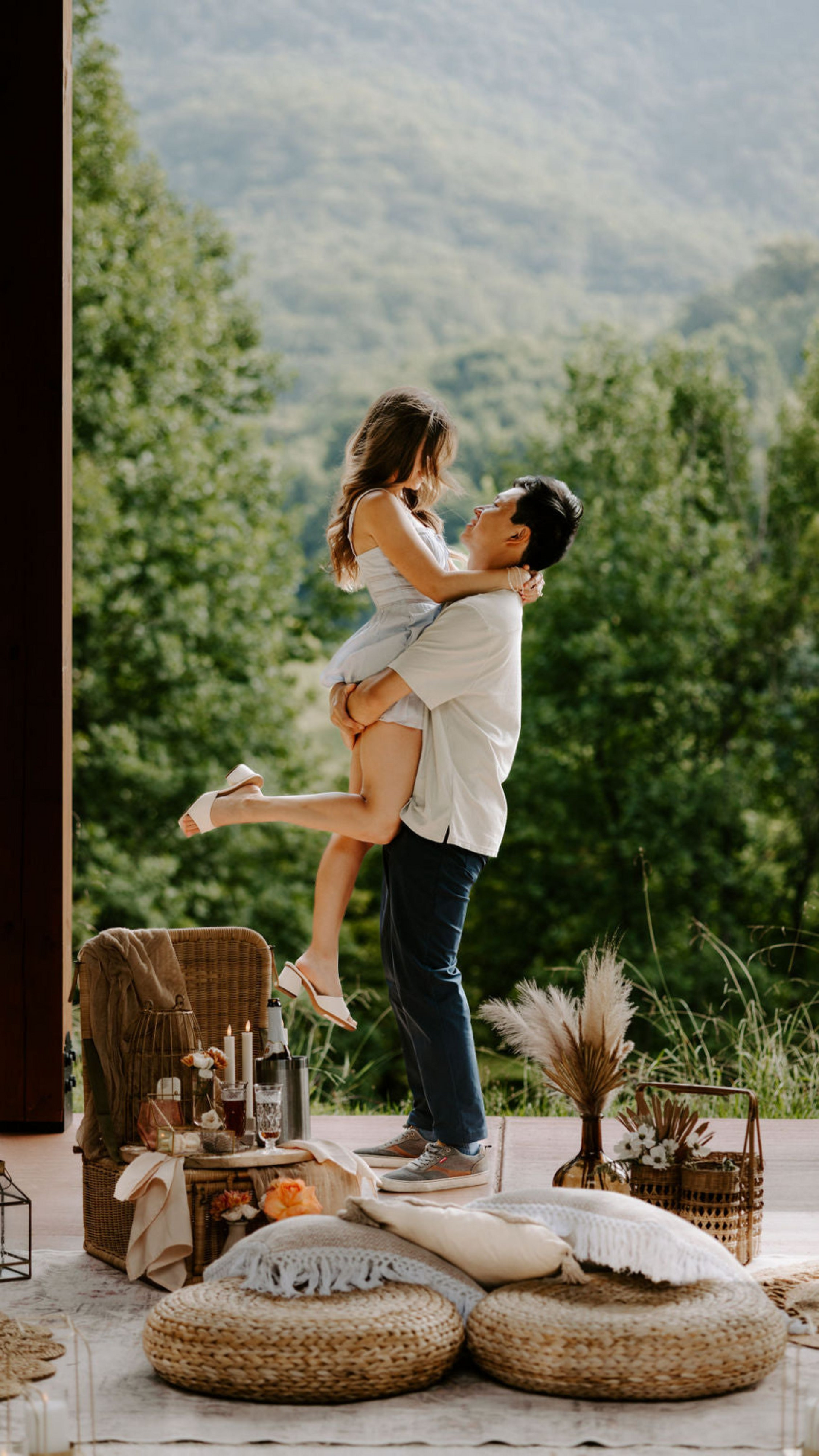 Man lifting a woman in a scenic outdoor setting with mountains and greenery. cute picnic country couple avl
